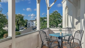 A covered outdoor area with a table and chairs, a view of buildings, and a clear sky.