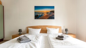 A double bed with white linens, two pillows, and folded towels.