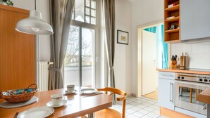A kitchen with a dining table, chairs, a basket, and a hanging light fixture.
