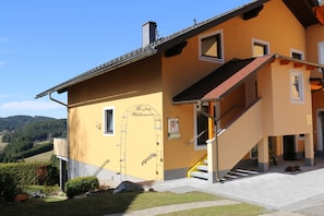 A yellow building with a staircase and a sign reading "Herzlich Willkommen".