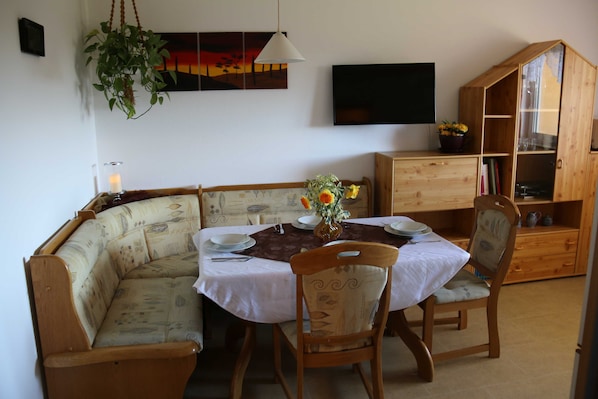 A dining area with a wooden table set for four, a cushioned bench, and a wooden cabinet with glass doors.