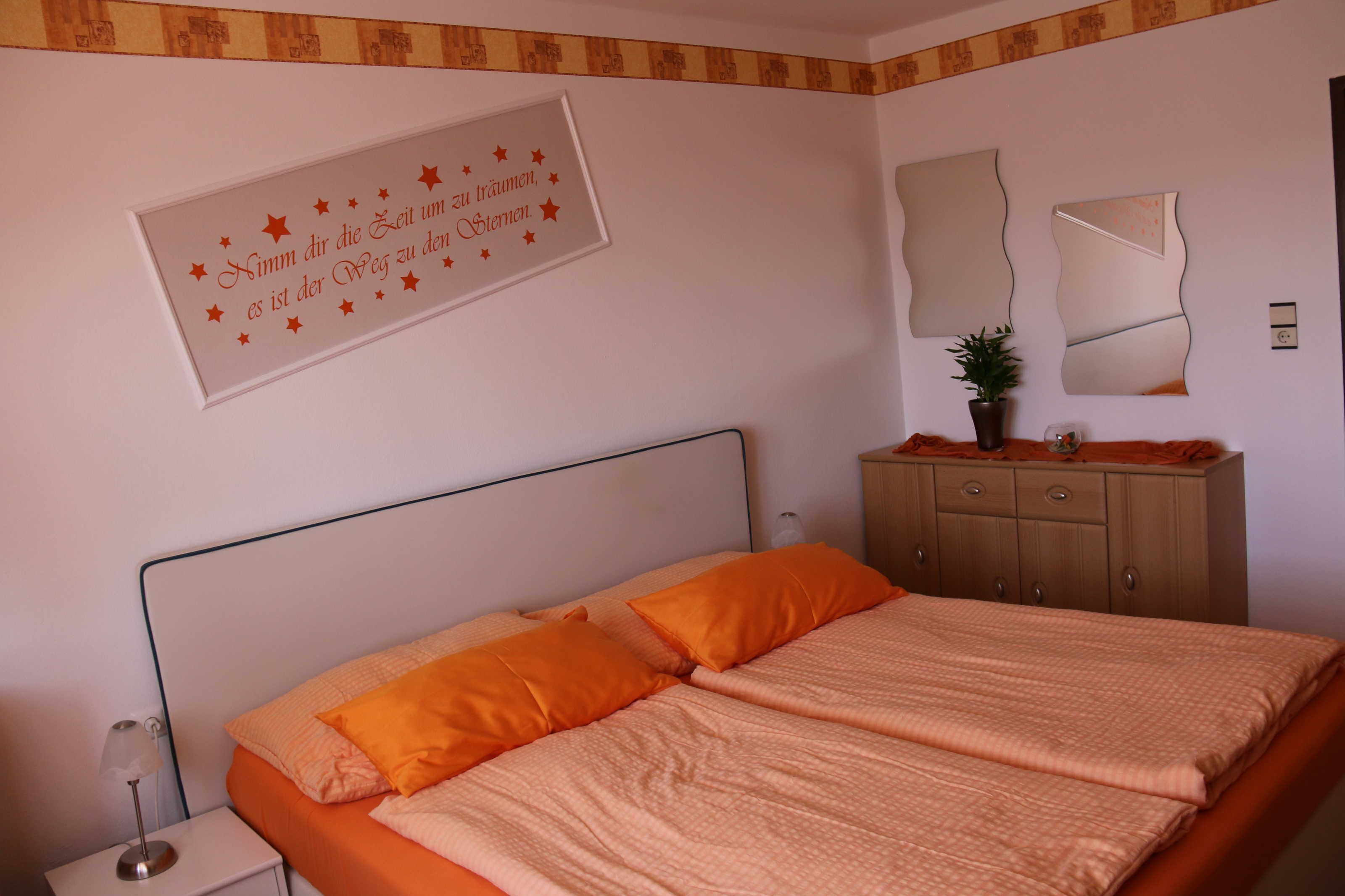 Ein Schlafzimmer mit Bett, Nachttisch, Kommode und Spiegel.