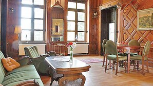 A traditional room with wooden paneling, a fireplace, a dining area with a table and chairs, and a large window with multiple panes. - Beautiful home in Schwasdorf with sauna (Schwasdorf)