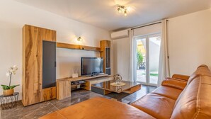 Un salon moderne avec un canapé en cuir, un téléviseur à écran plat et un meuble de rangement en bois.