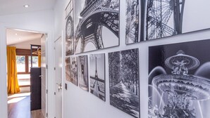 Um corredor com uma s érie de fotografias a preto e branco na parede, incluindo imagens da Torre Eiffel e de uma fonte.