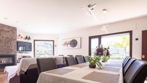 Uma sala de jantar moderna com uma mesa comprida, cadeiras de couro escuro e uma lareira.
