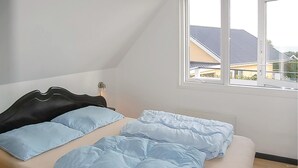 Ein Schlafzimmer mit einem Bett, einem Fenster und Blick auf Gebäude.