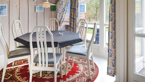A dining area with a round table, white chairs, and a red patterned rug. - 3 bedroom cozy home in Oksbøl (Oksbøl)