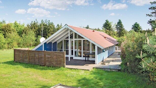 A small, single-story wooden cabin with a sloped roof, large windows, and a deck area. - 3 bedroom cozy home in Oksbøl (Oksbøl)