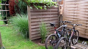 Un vélo est garé contre une clôture en bois dans un jardin.