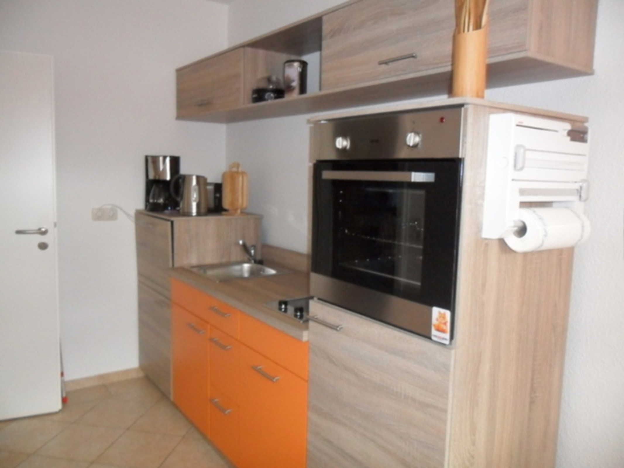 Una cocina compacta con horno integrado, un lavamanos y una encimera.