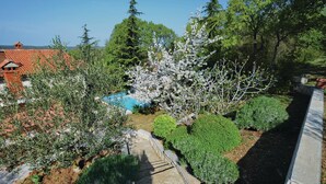 A garden with a swimming pool, various shrubs, and trees. - Gorgeous home in Reburici (Reburici)