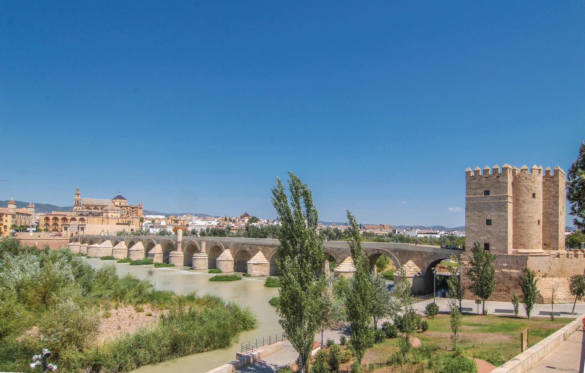Un ponte storico con diverse arcate, una struttura simile a un castello con merlature, e un fiume che scorre sotto.