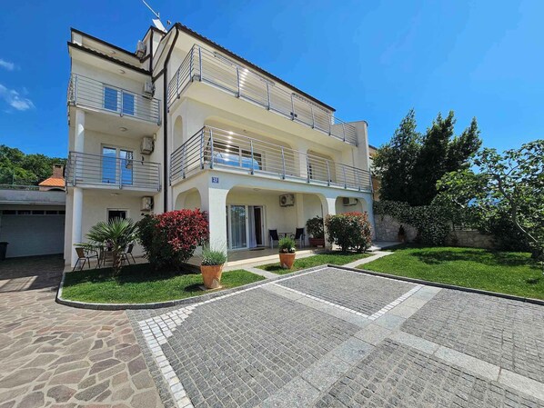 A two-story building with a balcony, a covered entrance, and a paved courtyard. - Studio for 2-3 persons with terrace (Novi Vinodolski)
