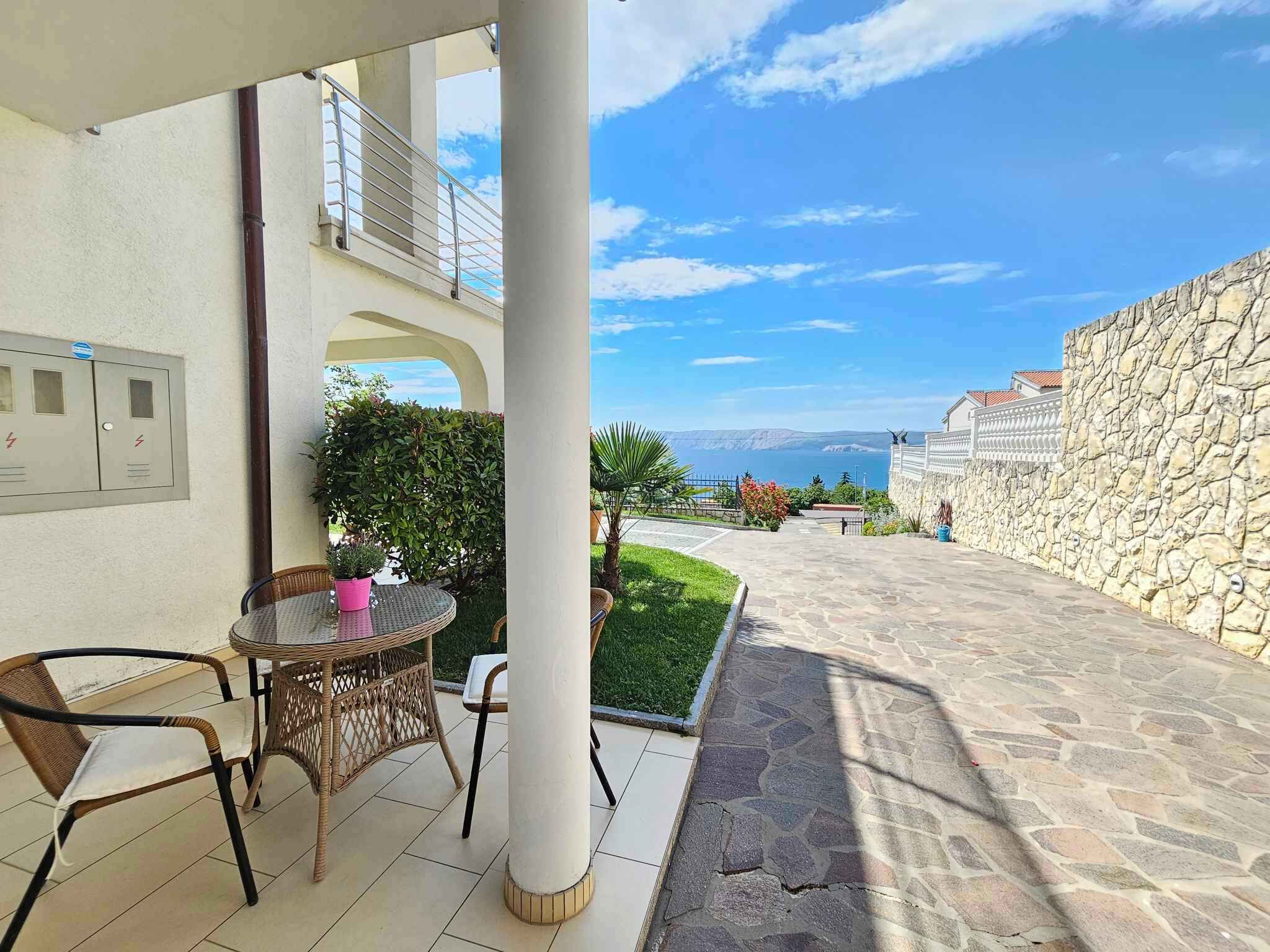 Un espacio al aire libre cubierto con una mesa, sillas, un muro de piedra y vistas al mar.