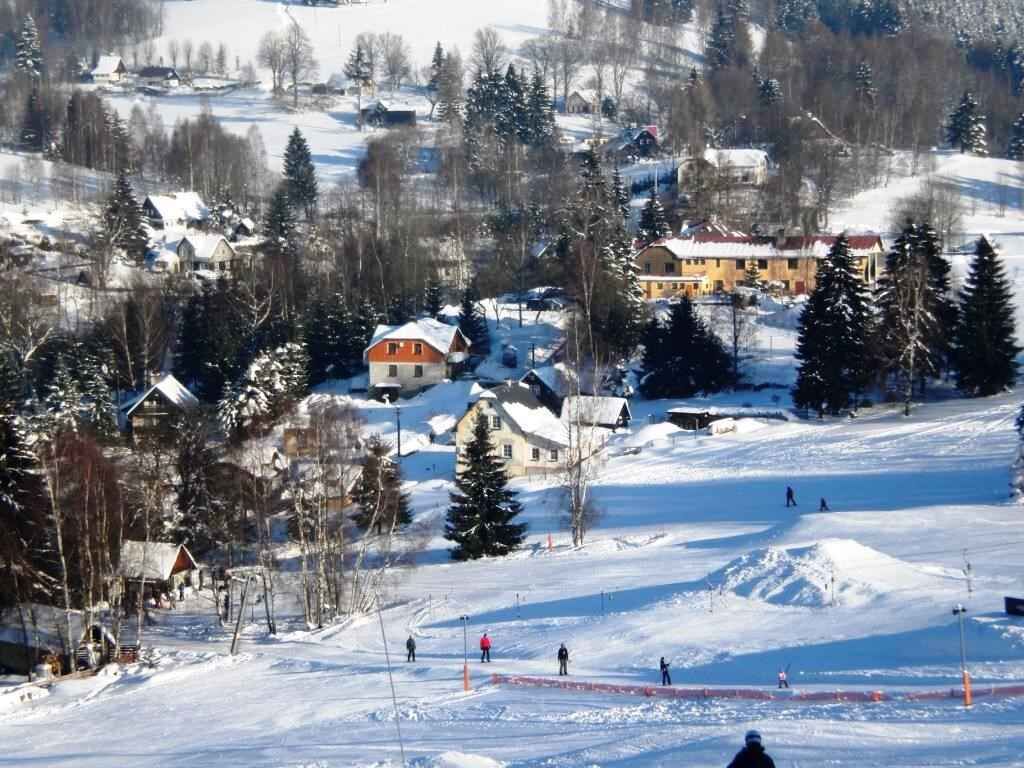 Estância de esqui coberta de neve, com edifícios, árvores e uma pista de esqui.