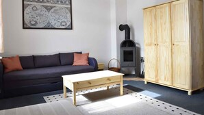 Een woonkamer met een bank, een houten tafel, een grote garderobe, een open haard en een inlijst kaart aan de muur.