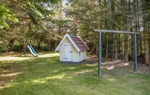 Enjoy a serene family-friendly setting with a playhouse and swing set amidst lush greenery.
