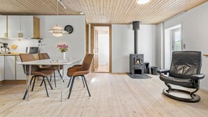 A modern living room with a dining area, a fireplace, and a large window. - 3 bedroom nice home in Brovst (Brovst)