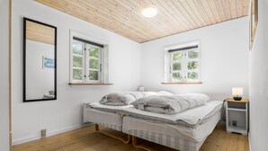 A bedroom with a bed, two windows, a bedside table with a lamp, and a wooden ceiling. - 3 bedroom nice home in Brovst (Brovst)