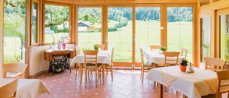 A conservatory with wooden beams, large windows, and a tiled floor.