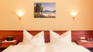 Ein Hotelzimmer mit einem Bett, zwei Nachttischen, einer Wandlampe und zwei Wandleuchten sowie einem Wandbild.
