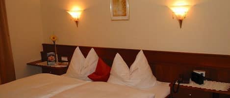 A hotel room with a bed, bedside tables, and wall-mounted lamps.