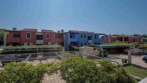 Une rangée d’immeubles résidentiels modernes à plusieurs étages, dotés d’un jardin sur le toit et d’un espace de stationnement.