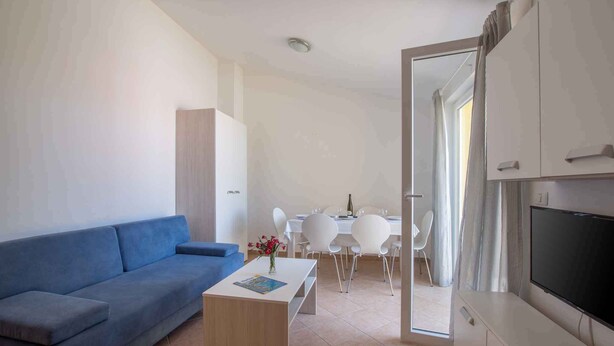 Un salon moderne avec un canapé bleu, une table basse en bois et un téléviseur à écran plat.