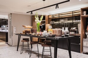 Una cocina moderna con una isla central, taburetes de bar y una variedad de alimentos y utensilios de cocina.