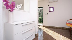 Un baño limpio y moderno con elementos blancos, un espejo y un florero con flores.