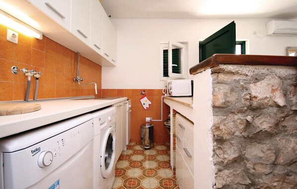 A compact kitchen with a washing machine, a microwave, and a stone wall. - 2 bedroom lovely home in Sparadici (Sparadici)