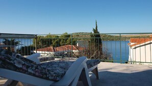 Un balcón con vistas a un lago, una silla y una barandilla.
