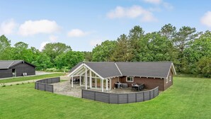 Et moderne hus med stor terrasse, overdækket patio og lade.