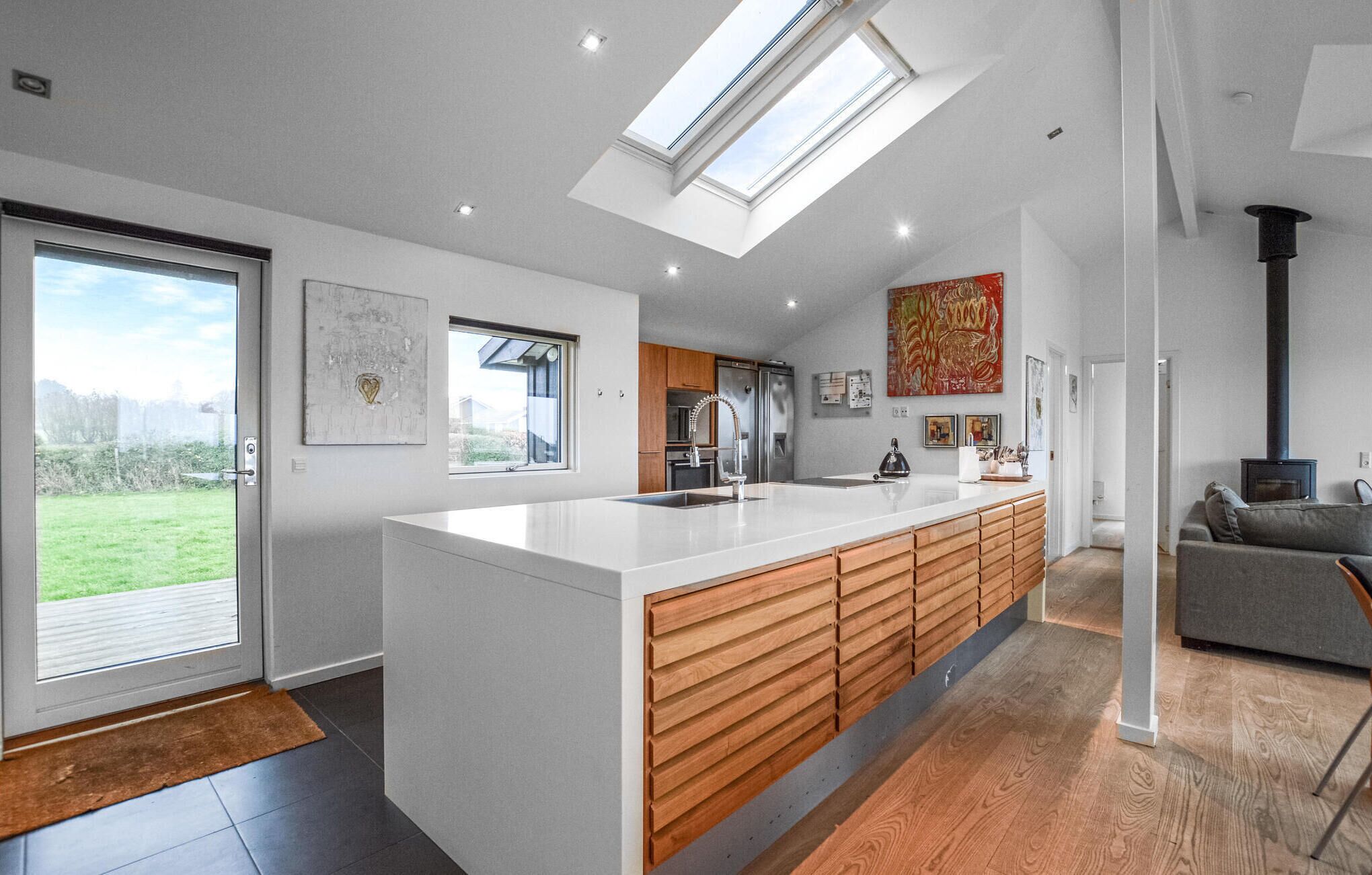 A modern kitchen with a large island, wooden cabinets, and a skylight.