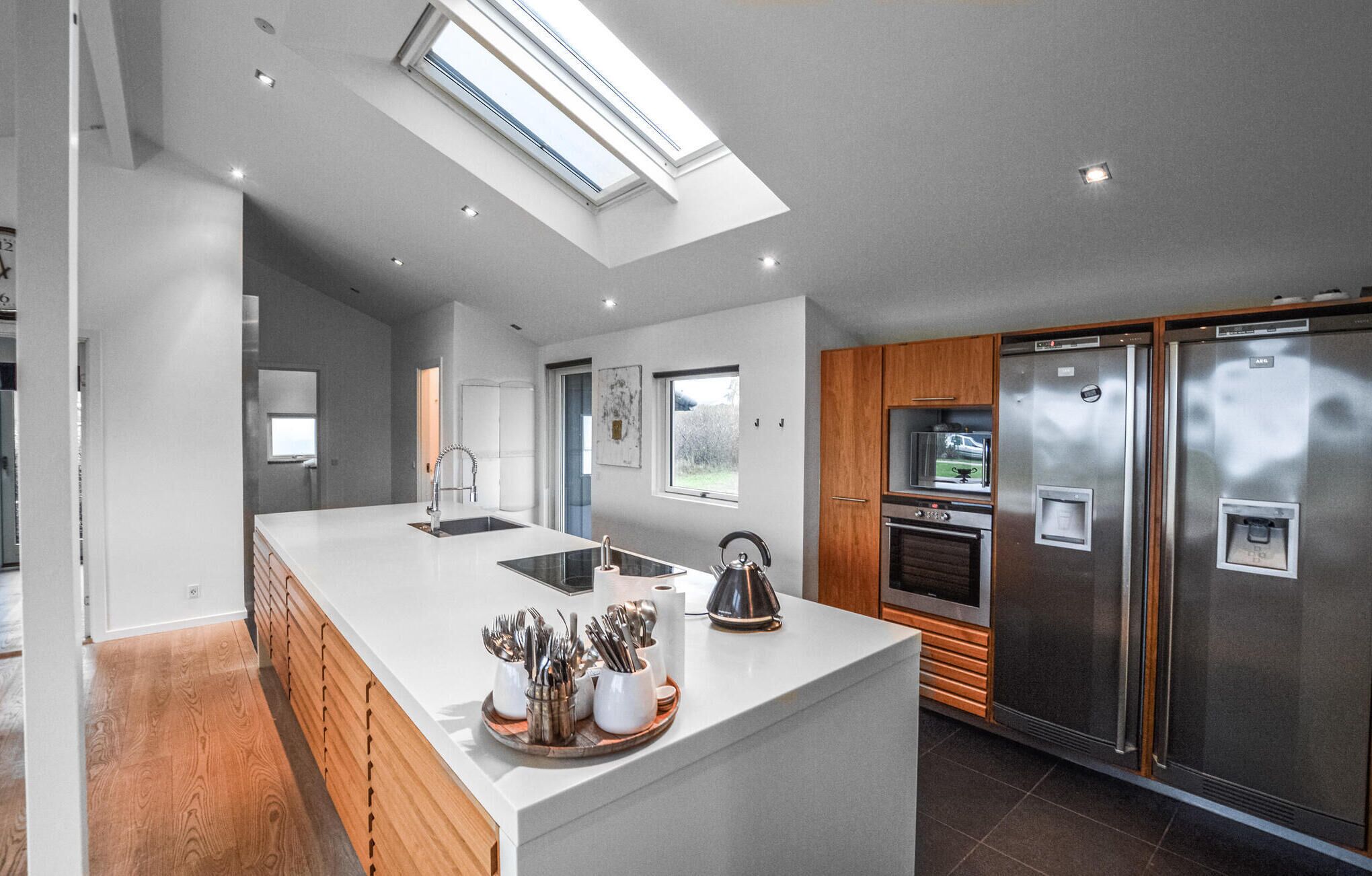 A modern kitchen with a central island, stainless steel appliances, and a skylight.
