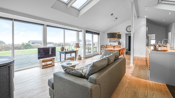 A spacious living room with a large sofa, a television, and a dining area with a table and chairs. - 3 bedroom amazing home in Slagelse (Slagelse)