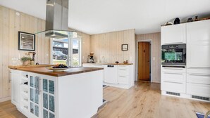 A modern kitchen with white cabinetry, a central island, and a large stove.