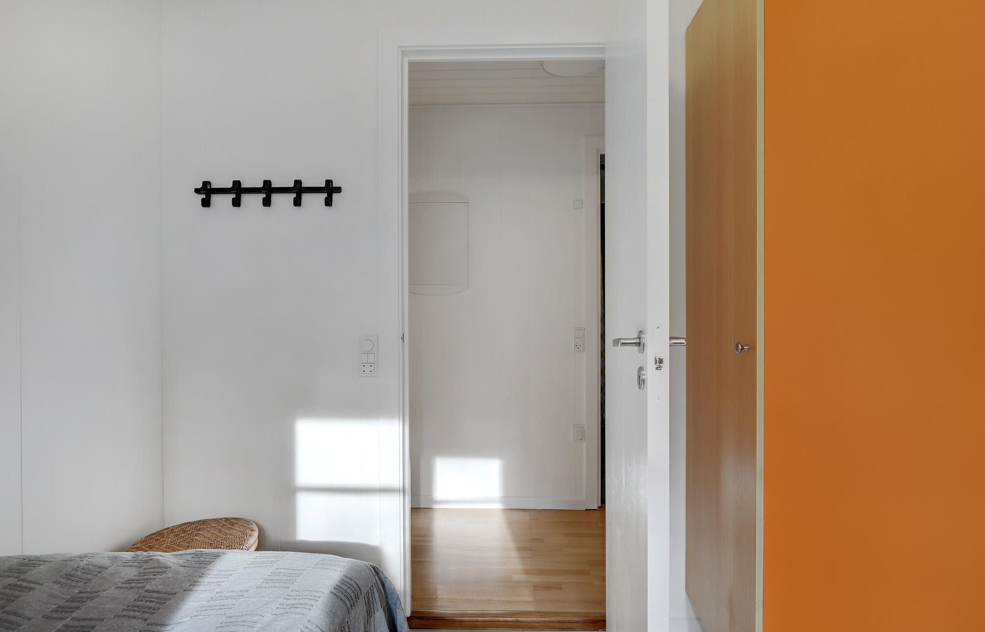 Una habitación con una cama, una puerta y un pasillo que conduce a otra estancia.