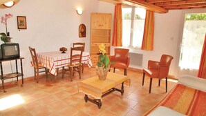 A cozy living room with a dining area, wooden furniture, a television, and a window with curtains. - 1 bedroom stunning home in Caderousse (Caderousse)