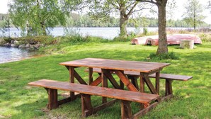 Un tavolo da picnic in legno con panche in una zona erbosa vicino a un lago.