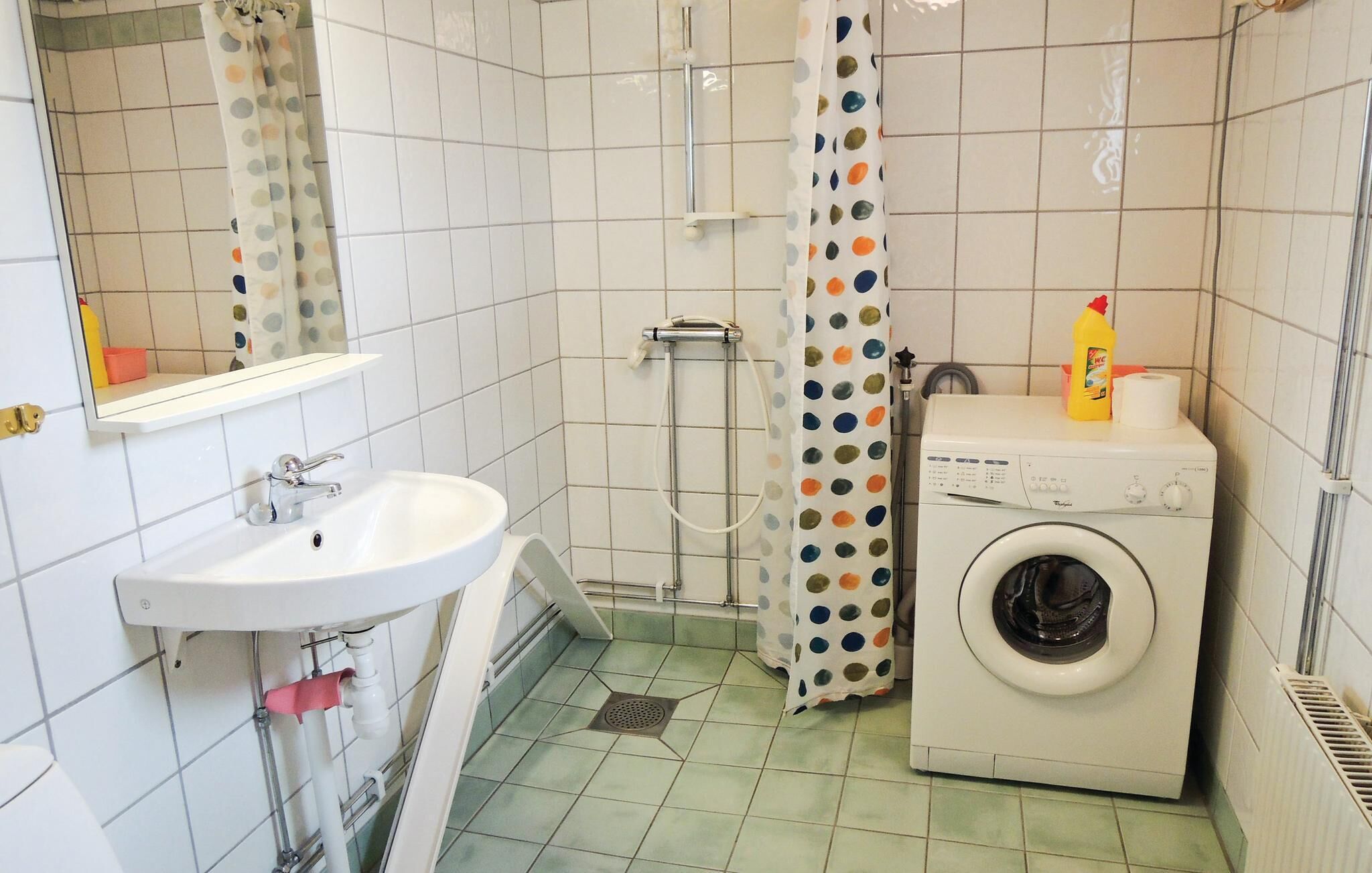 Une petite salle de bain avec un lavabo, une douche et un lave-linge.