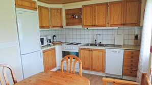 Una cucina compatta con mobili in legno, un frigorifero bianco, un piano cottura, un lavello e una lavastoviglie.