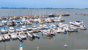 Una marina con diverse imbarcazioni ormeggiate, cielo sereno e acque calme.