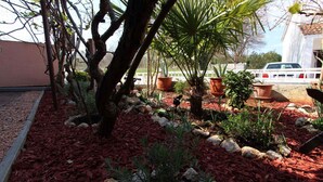 A garden with various plants, rocks, and a white fence. - Studio with balcony and air conditioning (Malinska)
