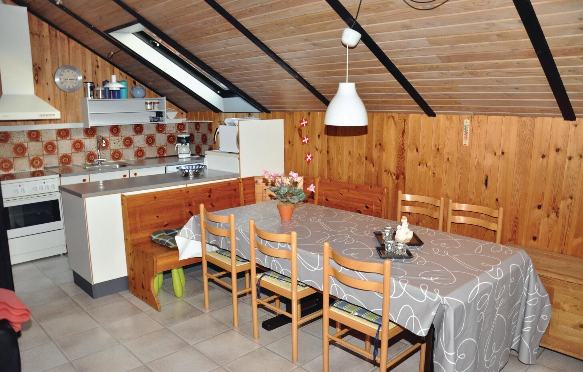 Une cuisine chaleureuse avec un coin repas, des murs en bois, une cuisinière moderne et une table à manger dressée pour quatre personnes.