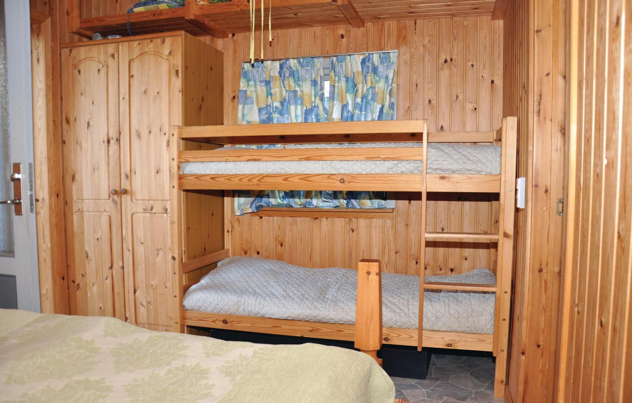 A wooden bunk bed room with a patterned curtain and a door.