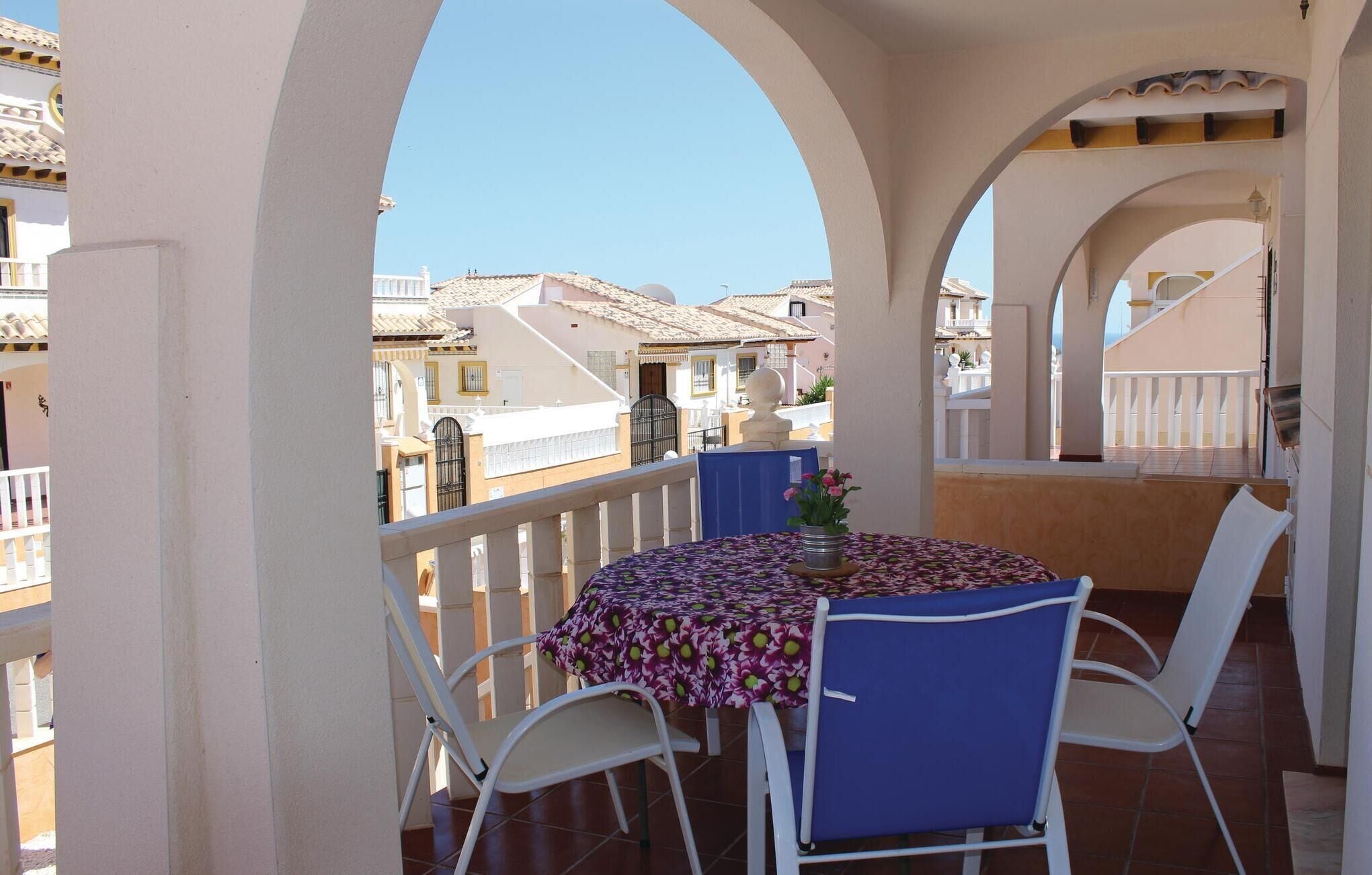 Een balkon met een tafel en stoelen, met uitzicht op een woonwijk met traditionele architectuur.