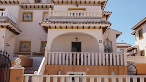 Ein mehrstöckiges Gebäude im traditionellen Baustil, mit Balkonen, rundbogigen Durchgängen und einem Ziegeldach.