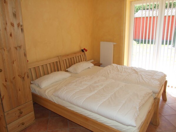 A wooden bed with white bedding in a room with yellow walls and a window with blinds. - Kajüte Vacation Home - - Kajüte Vacation Home - (Brodersby)